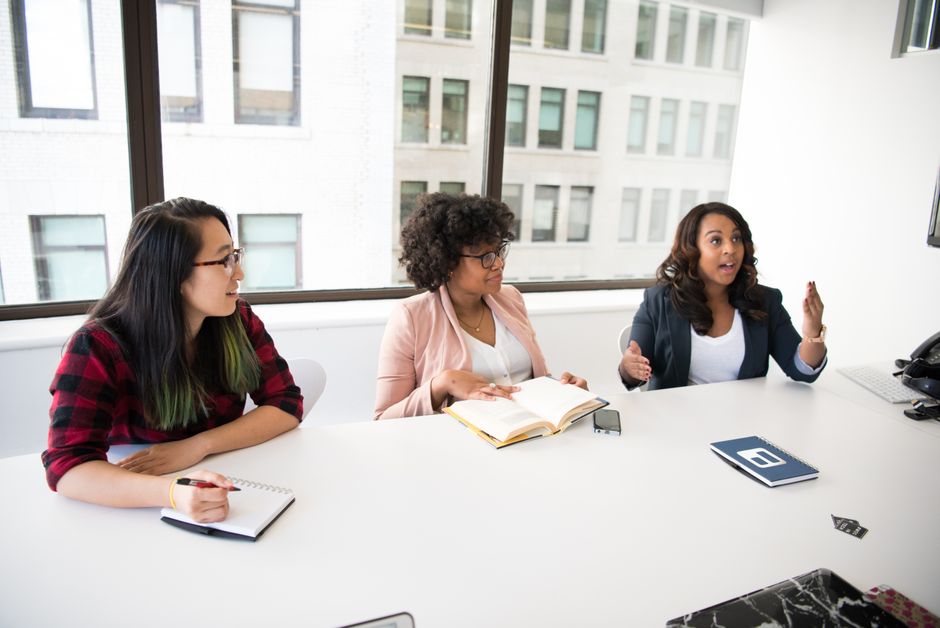 Grupo diverso de mujeres colaborando en una oficina moderna con monitores reacondicionados